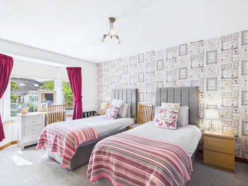 two beds in a bedroom with red curtains at Dunroamin Bed and Breakfast in Aviemore