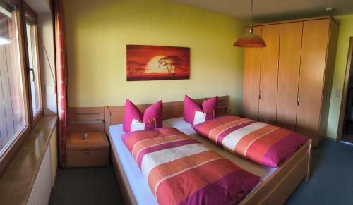 a bedroom with two beds with pink and purple pillows at Ferienwohnung Weiß inkl. Chiemgaukarte in Ruhpolding