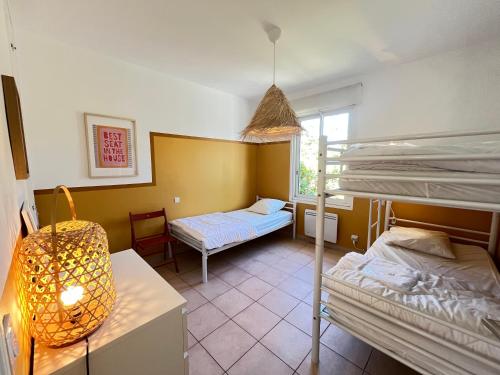 a room with two bunk beds and a table at Adorable maison de vacances plain pied au coeur de la station et proche des plages 4 chambres, jardin, WIFI, LXDUNE1 in Portiragnes