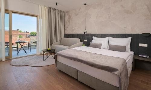 a bedroom with a bed and a chair and a balcony at Aminess Florian & Godler Hotel in Karlovac
