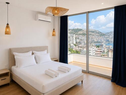 a bedroom with a white bed with a large window at Villa Saral Mar in Sarandë