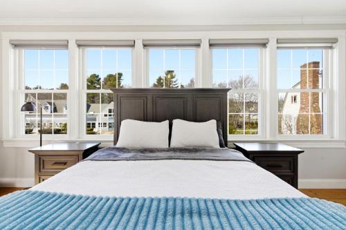 a bedroom with a bed with two tables and windows at Charming Kennebunk Cape - Walk to Dock Square! in Kennebunk
