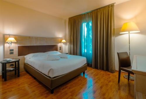 ein Schlafzimmer mit einem Bett, einem Schreibtisch und einem Stuhl in der Unterkunft San Giorgio, Sure Hotel Collection by Best Western in Forlì