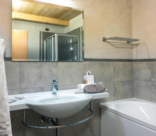 ein Badezimmer mit Waschbecken, Badewanne und Spiegel in der Unterkunft San Giorgio, Sure Hotel Collection by Best Western in Forlì