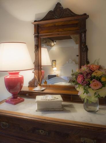 a table with a lamp and a mirror and flowers at Hotel Belvedere Di San Leonino in Castellina in Chianti