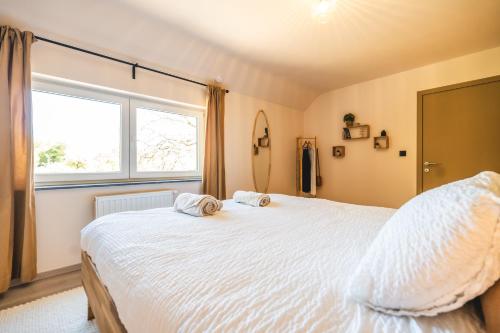 a bedroom with a white bed with two towels on it at Private spa - La Sparenthèse in Ciney