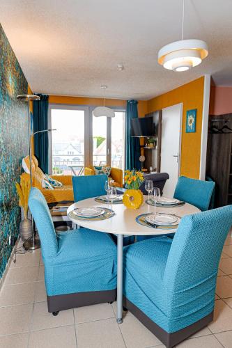 a dining room with a table and blue chairs at La villa Margats - Charme & détente en bord de mer in Bray-Dunes