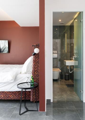 a bedroom with a bed and a table and a bathroom at 24K Athena Suites in Athens