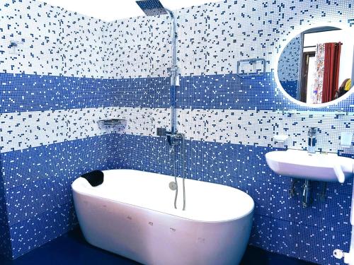 a blue tiled bathroom with a tub and a sink at cassiopeia escape in Kottawa