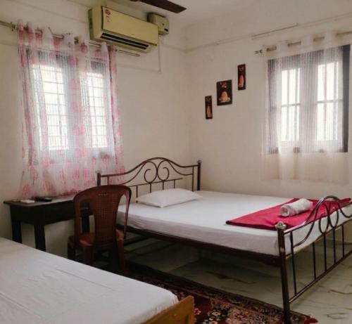 a bedroom with two beds and a desk and windows at Ebenezer Stay in Trivandrum
