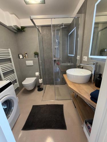 a bathroom with a shower and a sink and a washing machine at Studio Claudia in Opatija
