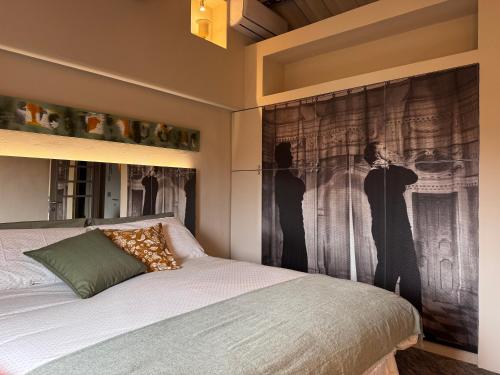 a bedroom with a bed with a large painting on the wall at La Casetta di Borgo Appartamento Albero in Lajatico