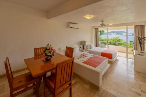 Pacifica Resort Ixtapa في اكستابا: غرفة فندق بها سرير وطاولة ومكتب