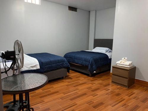 a room with two beds and a table and a desk at La Ruta in Paracas