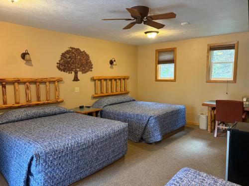 a bedroom with two beds and a ceiling fan at Glacier Highland Motel in West Glacier