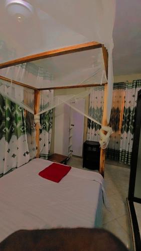 a bedroom with a canopy bed with a red towel on it at EBENEZER Apartment in Diani Beach