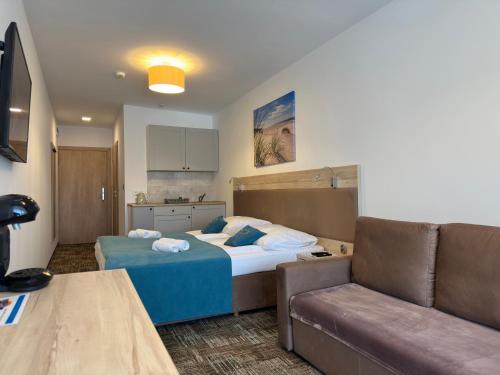 a hotel room with a bed and a couch at Apartament Suzi in Grzybowo