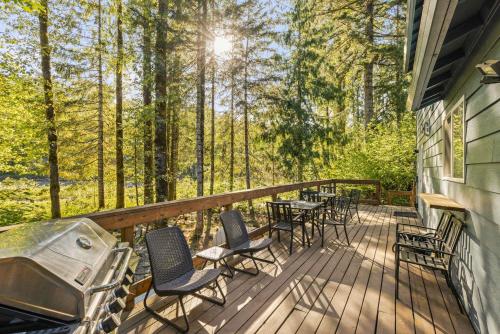 a deck with chairs and tables and a grill at Riverfront retreat with panoramic river and forest views in Rhododendron