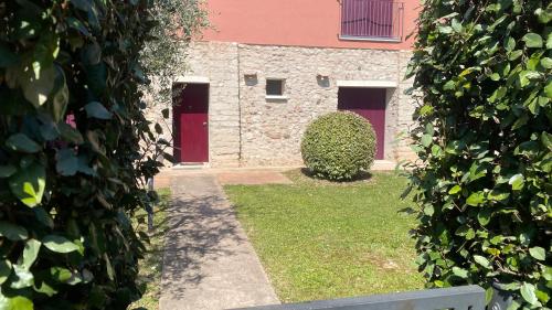 a building with two red doors and a hedge at Le Vele Del Cigno in Peschiera del Garda