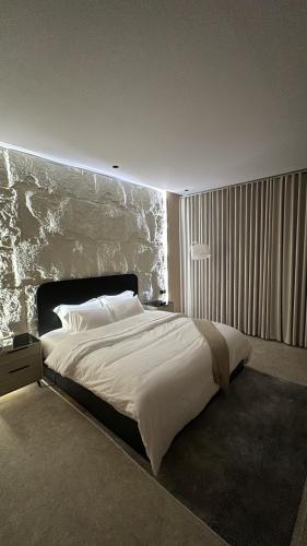 a bedroom with a large bed with a stone wall at شقة مفروشة أنيقة وهادئه in Al Ahsa