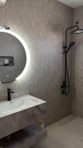 a bathroom with a sink and a large mirror at شقة مفروشة أنيقة وهادئه in Al Ahsa