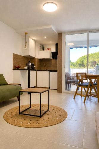 a living room with a table and a kitchen at Cosy Sunnyland, accès direct plage et parking privatif in La Grande Motte