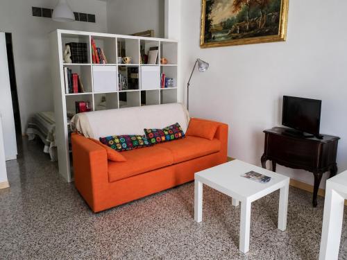 a living room with an orange couch and a white book shelf at Appartamento in Centro casa vacanza in Scicli