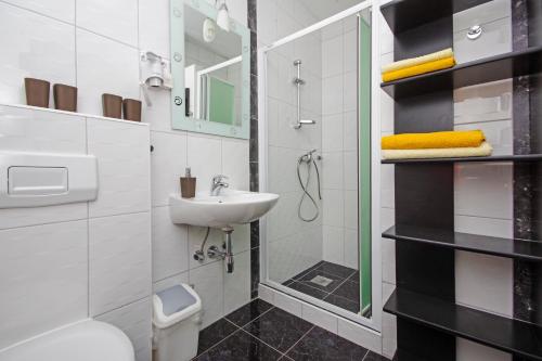 a white bathroom with a sink and a shower at Apartmani Villa Antonio in Makarska