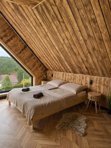 a bed in a room with a wooden ceiling at Przystań Ukoya in Koniaków