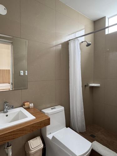a bathroom with a white toilet and a sink at Betania in Paracas