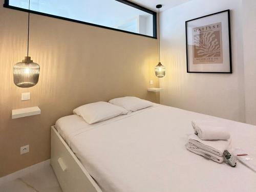 a bedroom with a bed with two pillows and a window at Le Soleil Tropézien, Somptueux 2 pièces - Terrasse Vue Mer in Menton