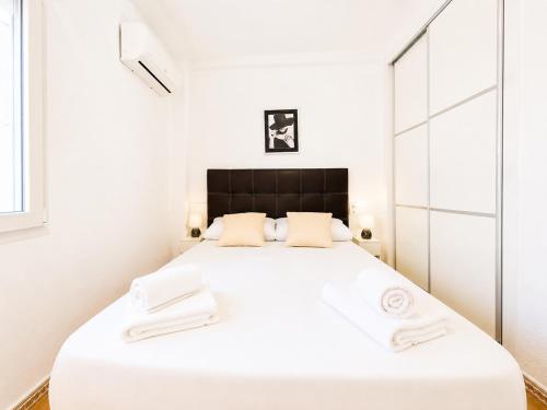a white bedroom with a large white bed with two white towels at Bungalow Oaxaca: Playa de La Mata in Torrevieja