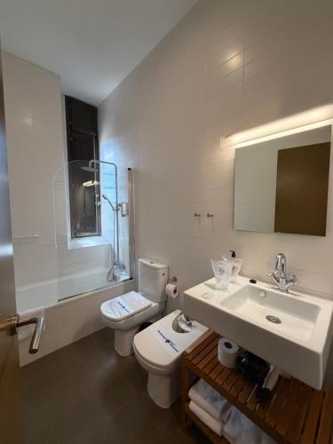 a white bathroom with a toilet and a sink at Hospedería de Alesves in Villafranca