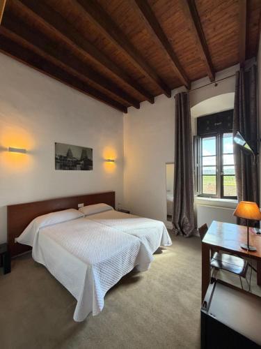 a bedroom with two beds and a desk and window at Hospedería de Alesves in Villafranca