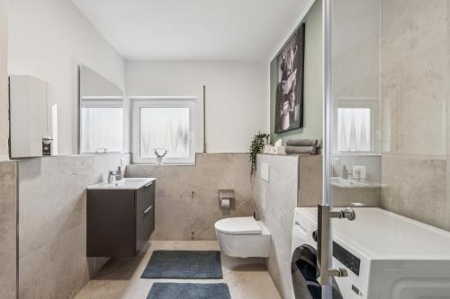 a white bathroom with a toilet and a sink at SleepHaven in Walldürn