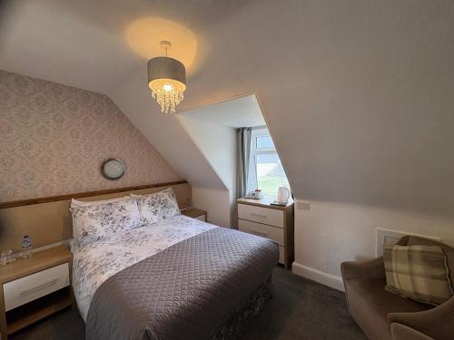 a bedroom with a bed and a chair and a window at Glendale Guesthouse in Oban