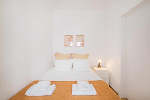 a white bedroom with a white bed with two towels at Vista del Mar Guest House in Albufeira
