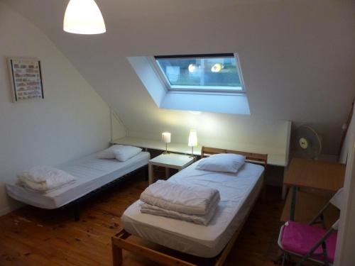two beds in a room with a window at Maison familiale Villa Eolie, 10mn de la mer en voiture in Tregueux