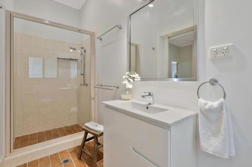 a white bathroom with a sink and a shower at Salty Beach in Amity Point