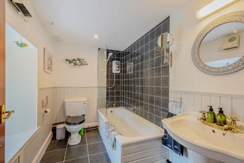 a bathroom with a tub and a toilet and a sink at Smithy House in Lochgilphead