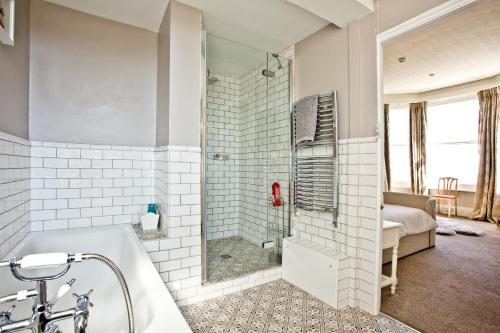 a bathroom with a shower and a bath tub at Woodend Seaside Villa in Torquay