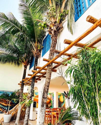 a group of palm trees in front of a building at Pousada Areias do Pero in Cabo Frio