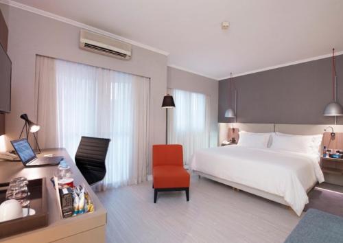 a bedroom with a white bed and a red chair at Clarion Faria Lima in São Paulo