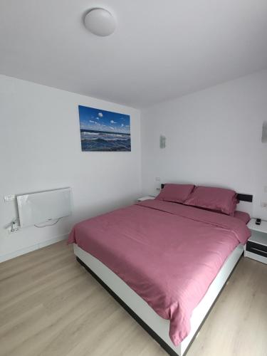 a white bedroom with a large bed with pink sheets at Cozy apartment Vama Veche in Vama Veche