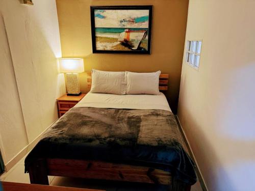 a small bedroom with a bed and a picture on the wall at Arubaapartamentos in Oranjestad