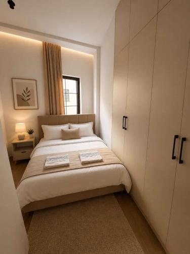 a white bedroom with a bed and a window at Hotel Berati in Prizren