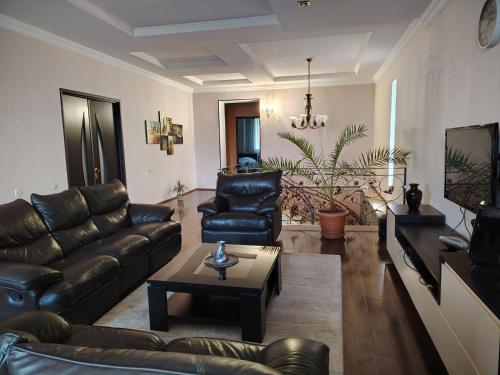 a living room with leather couches and a table at Marinella in Telavi