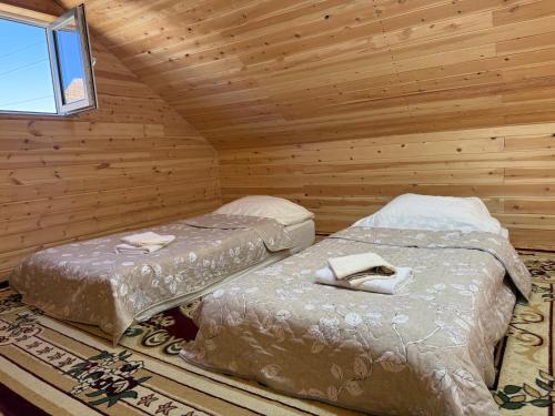 two beds in a wooden room with a window at Naryn Barnhouses in Naryn