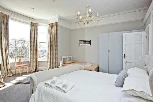 a bedroom with a large white bed and a chandelier at Woodend Seaside Villa in Torquay