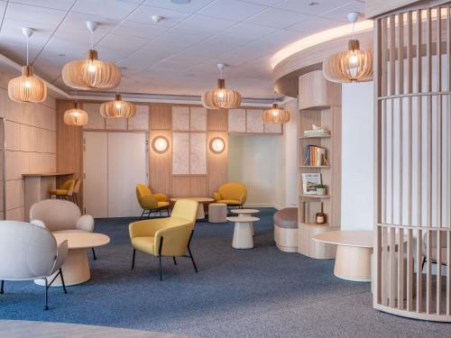 a waiting room with tables and chairs and lights at Novotel Marseille Centre Gare in Marseille